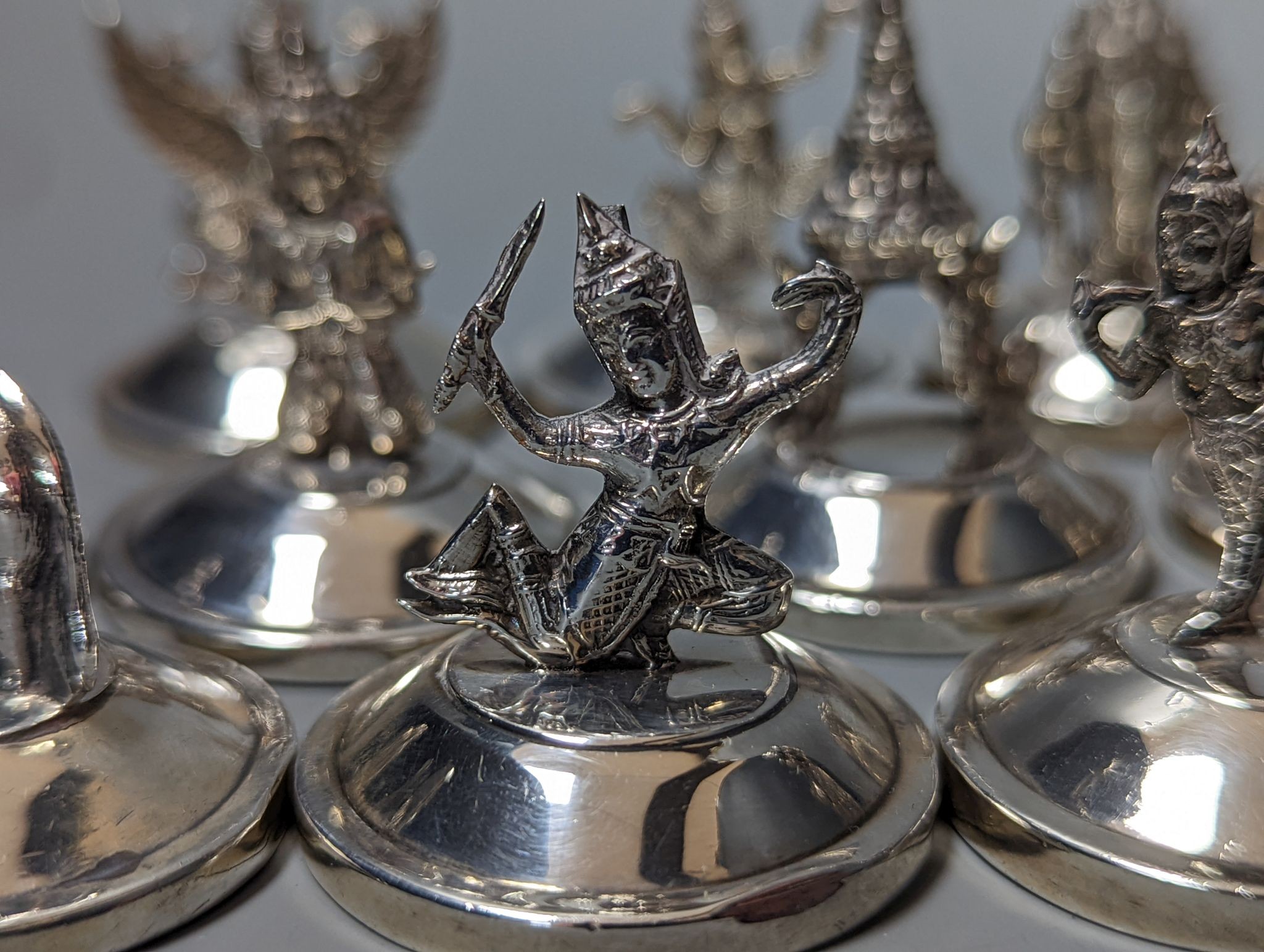 Sixteen assorted Siamese sterling mounted menu holders, modelled with figures, elephant, etc.